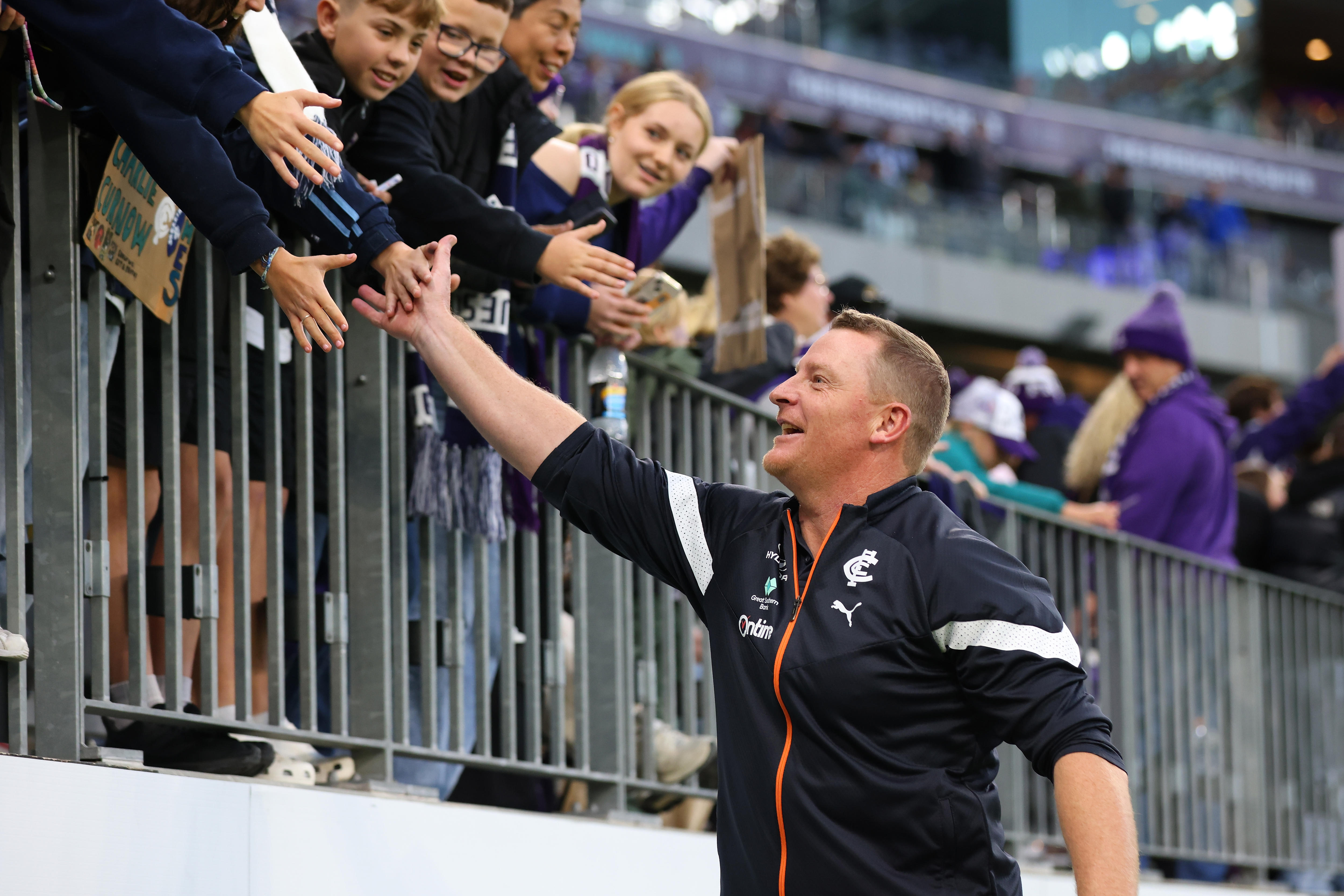 Michael Voss shares a high five with Carlton fans in the stands
