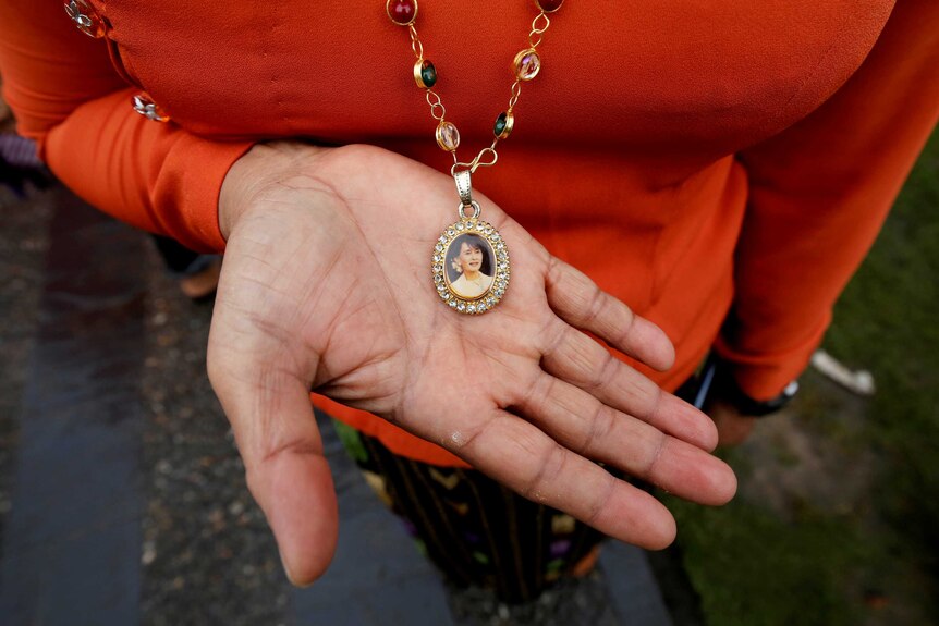 A woman with a necklace around her neck with a picture of Aung San Suu Kyi on the pendant
