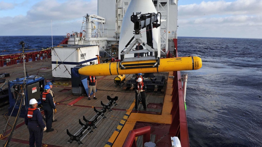 Crew on the Ocean Shield use a crane to lower the Bluefin-21 autonomous underwater vehicle into the water.