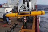 Crew on the Ocean Shield use a crane to lower the Bluefin-21 autonomous underwater vehicle into the water.
