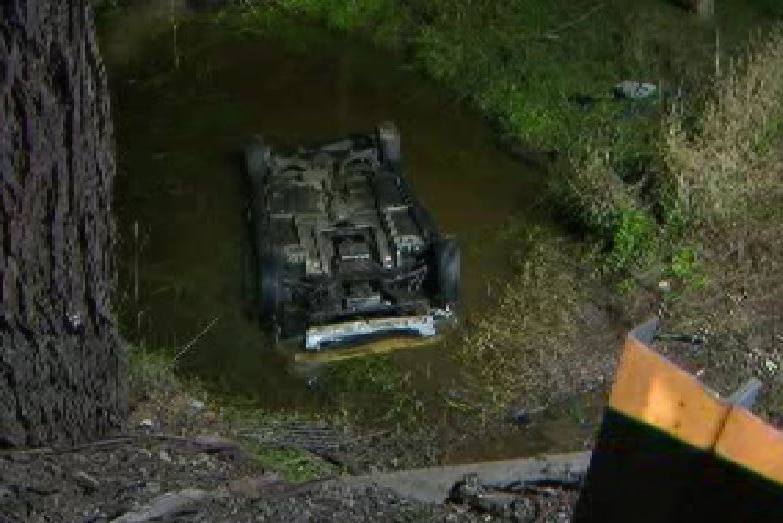 A car rolled over on its roof in a creek.