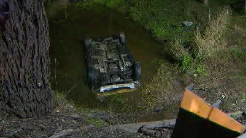 A car rolled over on its roof in a creek.
