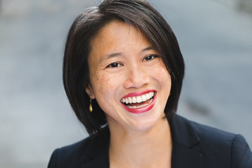Portrait of a professionally dressed middle-aged woman with short black hair and a big smile.
