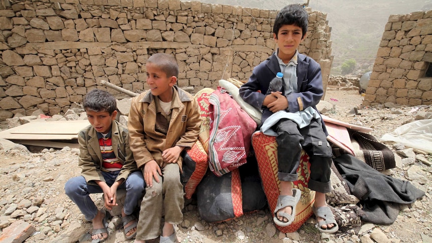 Boys sit on belongings at the rubble of houses destroyed by an air strike in the Okash village near Sanaa April 4, 2015