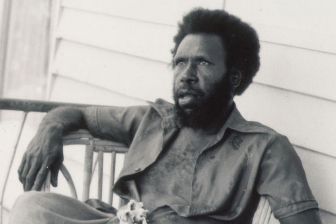 A black and white photo of a man reclining on a chair.