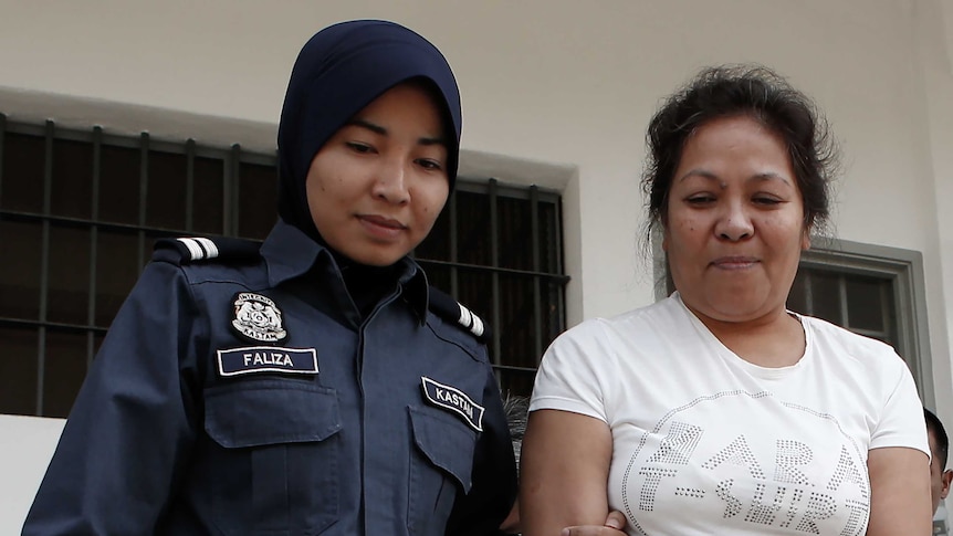 Maria Elvira Pinto Exposto escorted by a Malaysian customs officer outside court in Sepang, Kuala Lumpur