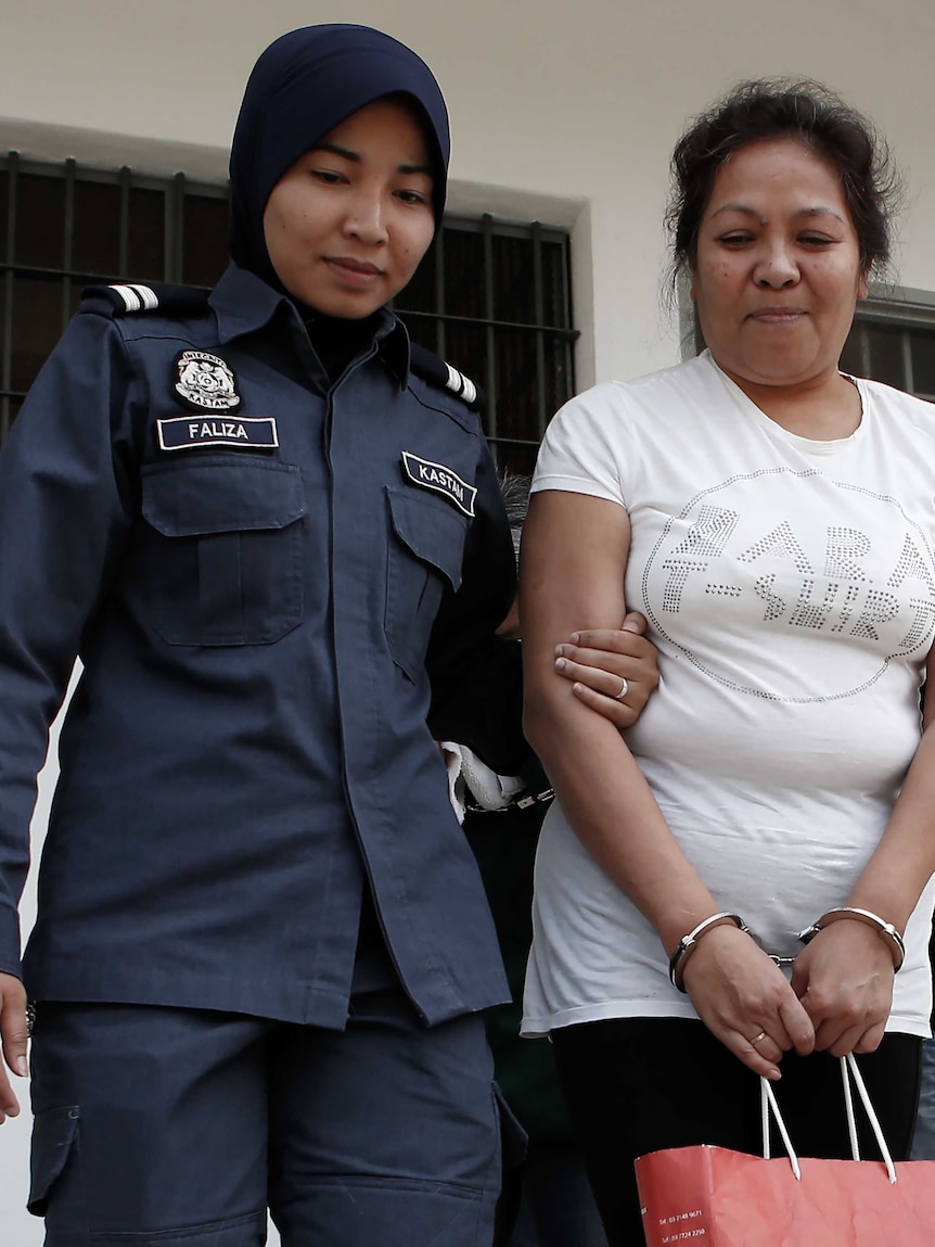 Maria Elvira Pinto Exposto escorted by a Malaysian customs officer outside court in Sepang, Kuala Lumpur