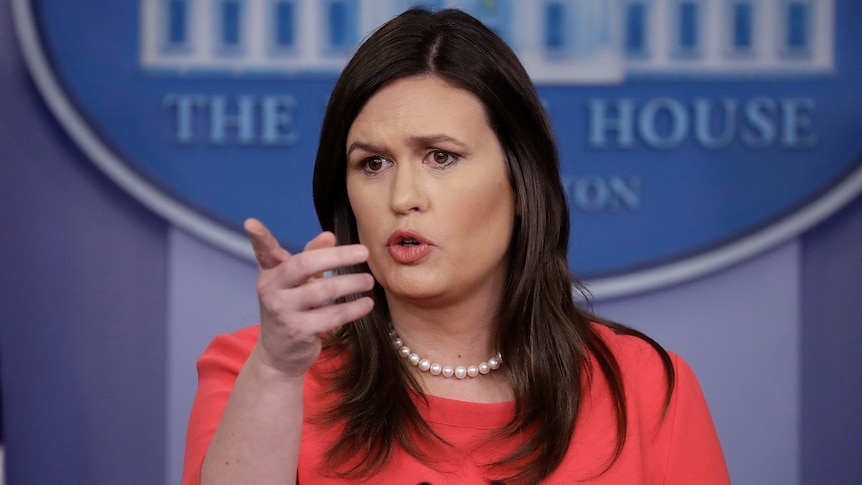 A woman points as she speaks from behind a lecturn