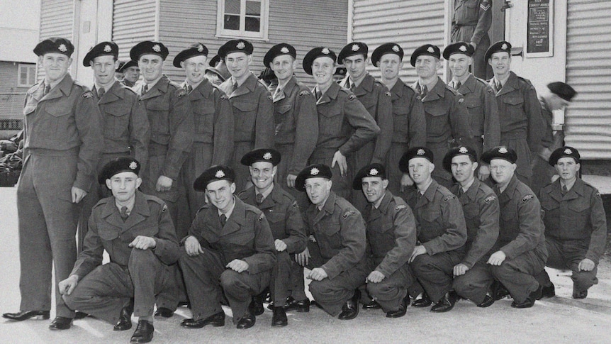 A black and white photo taking in 1955 of 21 young men in army uniform forming two rows outside the platoon hut.