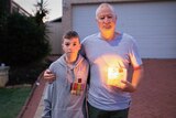 A man holds a candle and his son wears his grandparents' service medals.