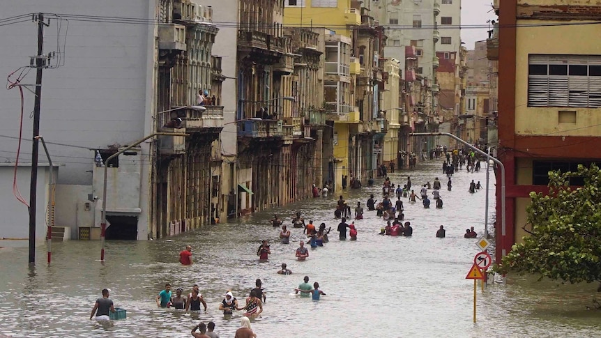 People trudge through waist deep water in central Havana.
