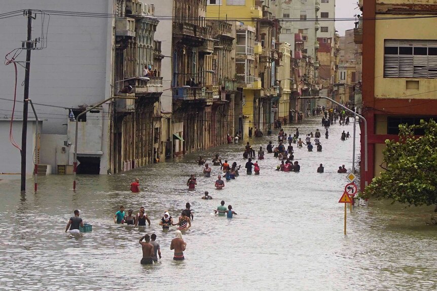 People trudge through waist deep water in central Havana.