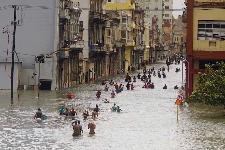 People trudge through waist deep water in central Havana.