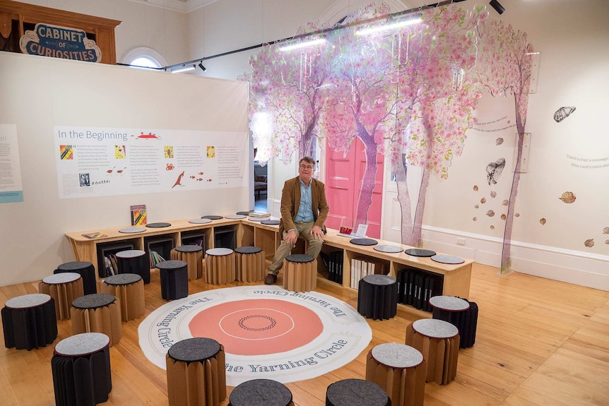 Man sits a library circle decorated with cherry trees.