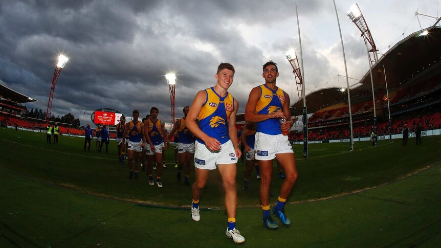 West Coast Eagles players Brayden Ainsworth and Brendon Ah Chee walk off the ground with their teammates behind them.