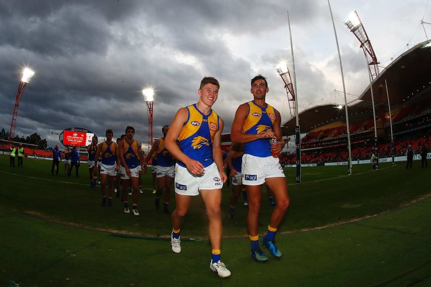 West Coast Eagles players Brayden Ainsworth and Brendon Ah Chee walk off the ground with their teammates behind them.