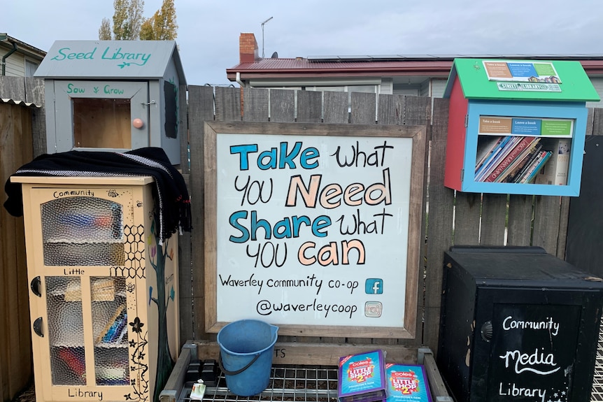 A sign says,'Take what you need, share what you can, Waverley community co-op'.