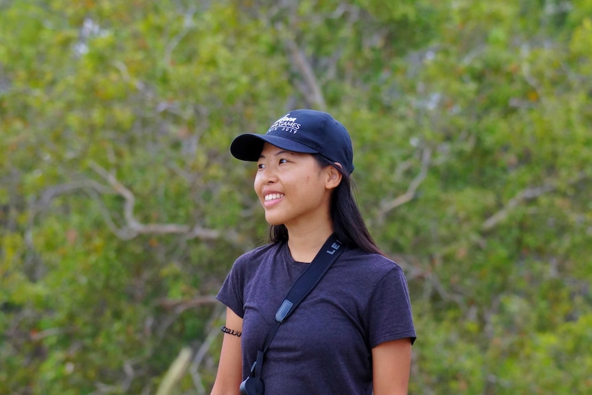 Tisha looks off to the left hand side wearing a navy cap and a blue t-shirt.