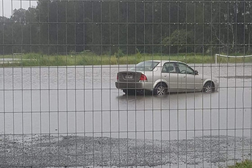 A car is surrounded by flood water.