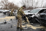 Russian soldiers pour sawdust on to road where a missile attack struck cars in Belgorod