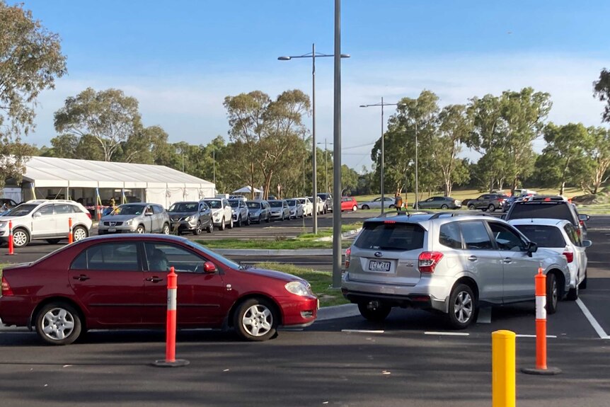 A long line of cars at a drive-through coronavirus testing site on a sunny Melbourne day.