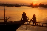 Two young boys stare out at the sunset over the bay in the Philippines.