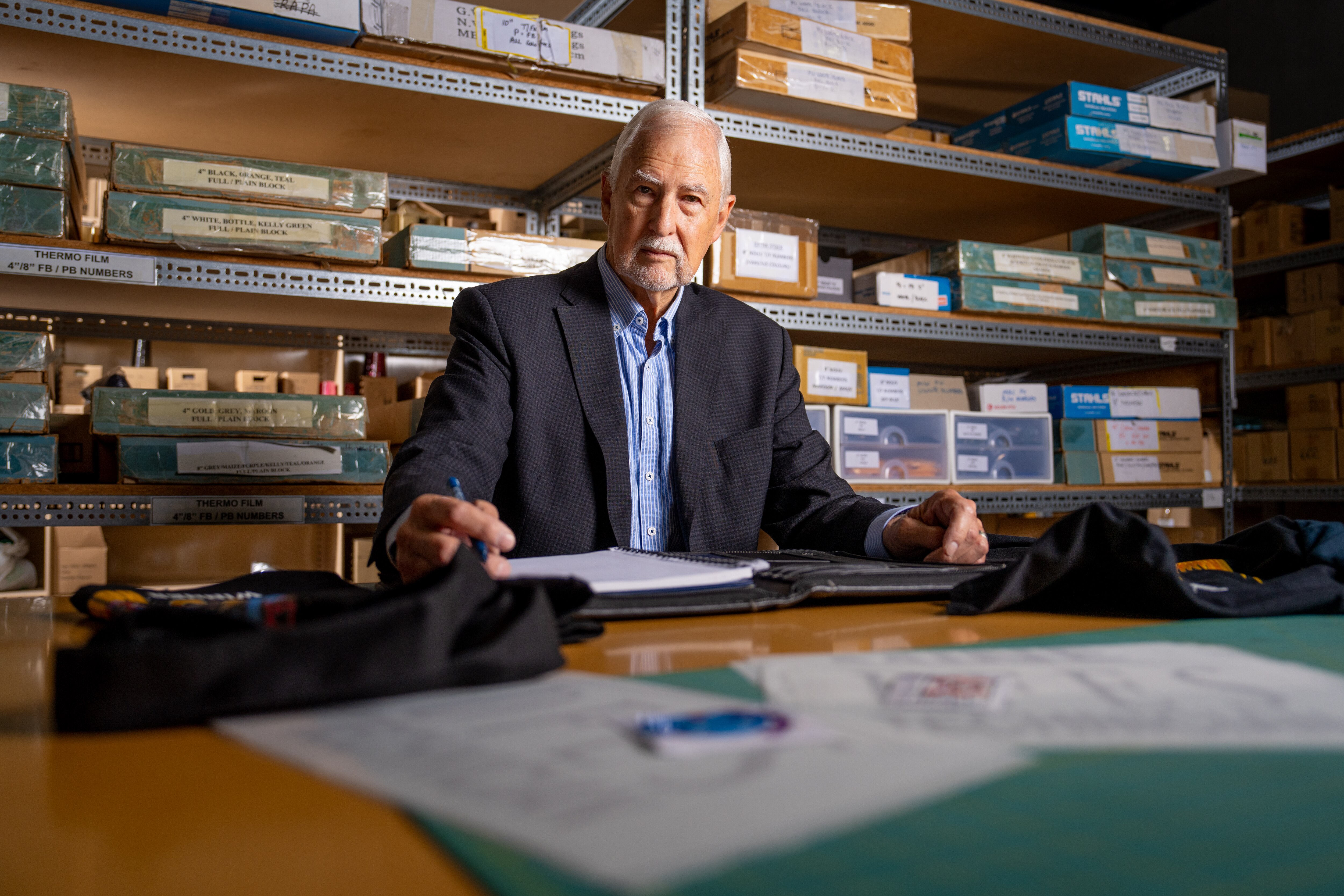 Un hombre mira a la cámara desde su escritorio con un bolígrafo en la mano