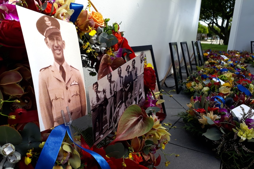 A sepia-toned photo of a young man in an RAAF uniform in the centre of a flower wreath, other photos of young men behind it