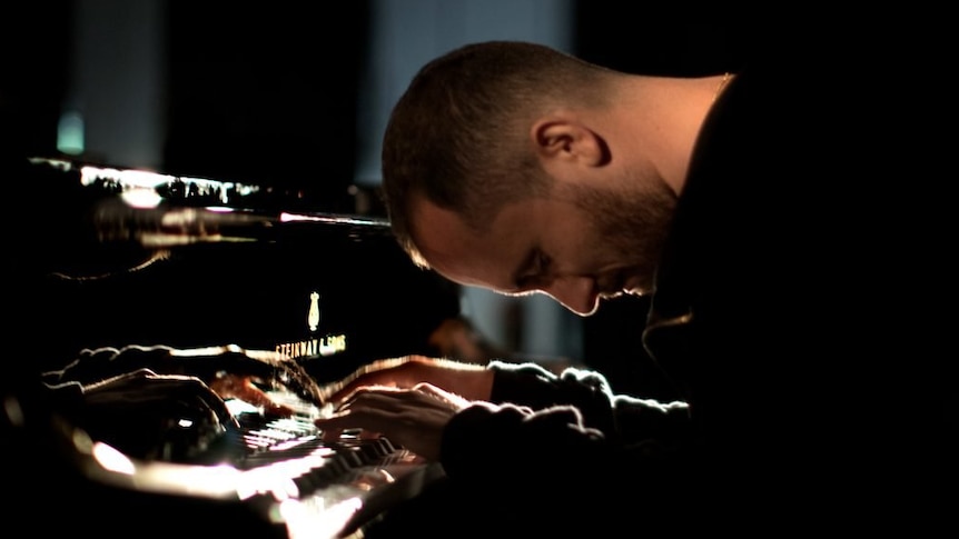 Igor Levit with head bowed over his piano.