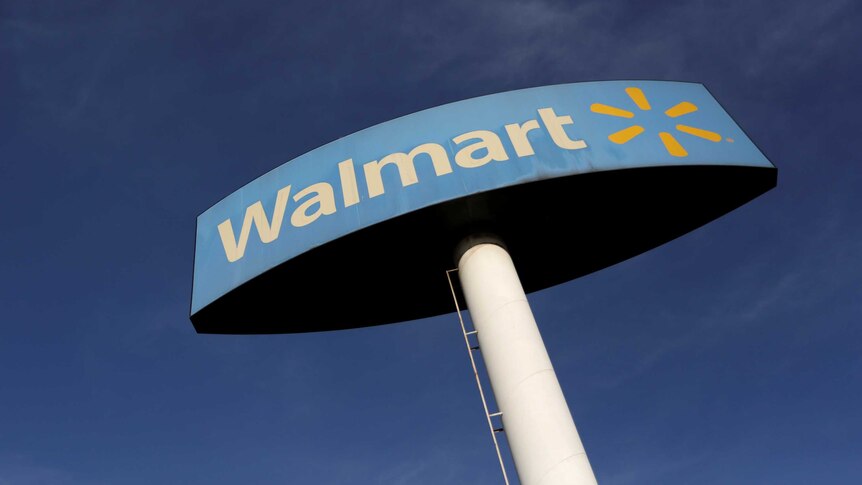 A Walmart sign is pictured against a blue sky.