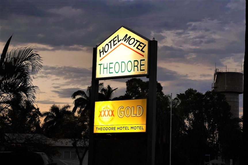 A sign saying Hotel Motel Theodore XXXX Gold Theodore Hotel Motel is illuminated against a night sky.