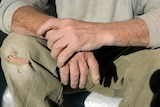 Male labourer's hands resting on knee