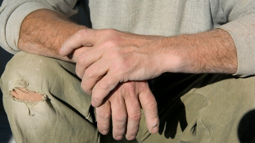 Male labourer's hands resting on knee