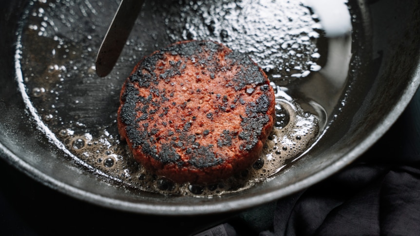 A lamb burger frying in a pan