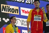China's Sun Yang (centre) holds up his gold medal as silver medalist Australia's Mack Horton (left) stands away from the podium.