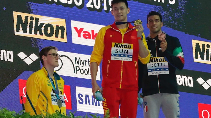 China's Sun Yang (centre) holds up his gold medal as silver medalist Australia's Mack Horton (left) stands away from the podium.