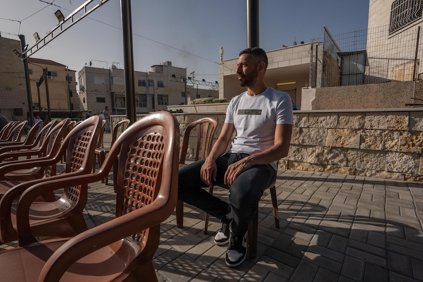 Un joven de Oriente Medio sentado en una silla en el techo de una casa 