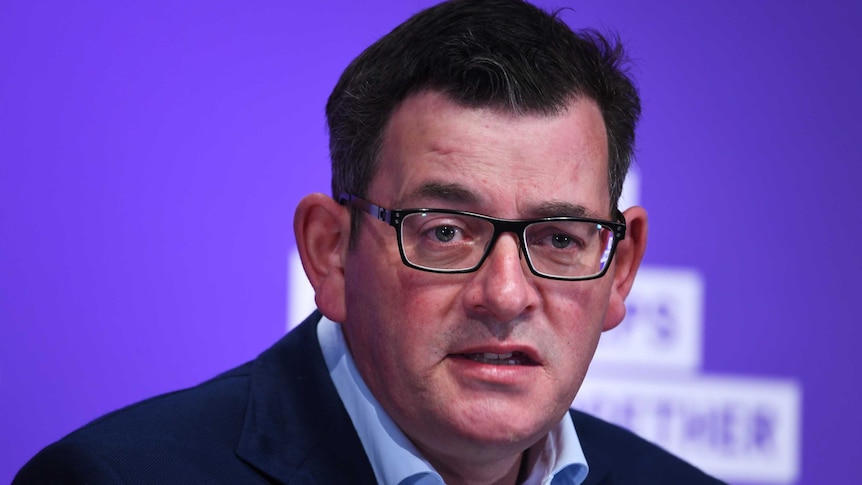 A bespectacled middle aged man with dark hair looks toward the camera as he speaks.