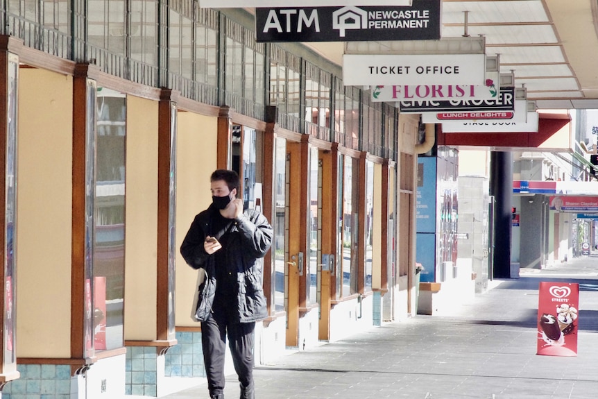 A man wearing a face mask walking down an empty street.