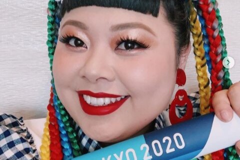 Naomi Watanabe holds a baton with Tokyo 2020 on it