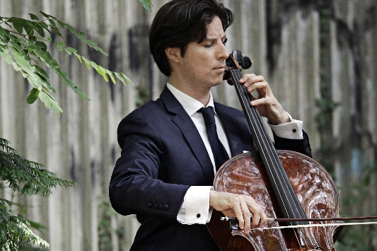 Cellist Daniel Muller-Schott playing cello outdoors.