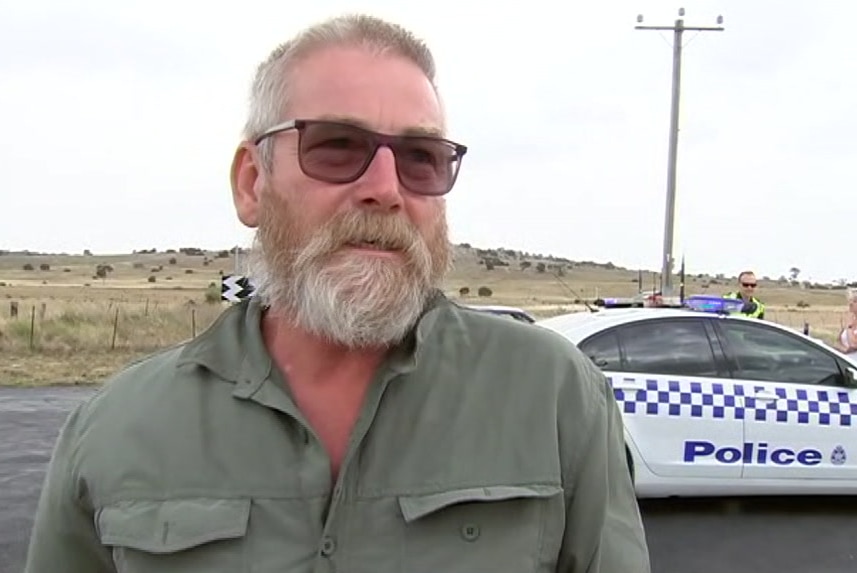 John Stevens stands at a police road block near the Little River fire with a police car in the background.