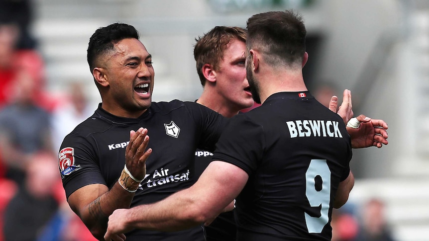 Two Toronto Wolfpack players smile and get ready to embrace.
