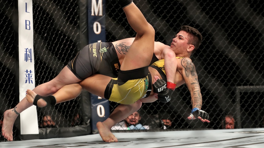A UFC fighter tackles another in the octagon.