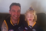 A man holding a girl on a sofa, both wearing Adelaide Crows jumpers