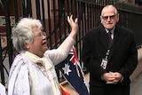 two women in white holding anti-abortion signs with older man in black coat and sunglasses next to them