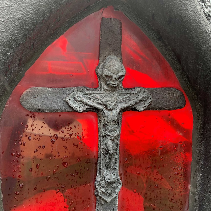 Picture of red stained glass window on hears with silver cross.