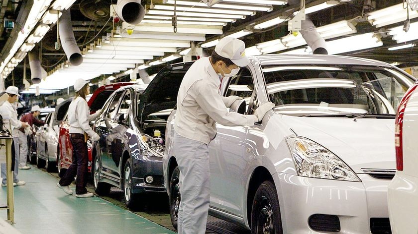 Workers install parts onto Toyota vehicles on the assembly line of the company's Tsutsumi factory in