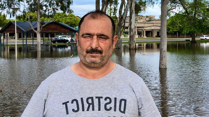 A man standing with flood water behind his back.