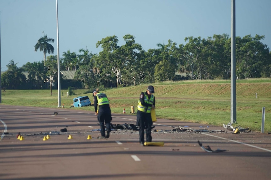 Two police officers lay out markers on a road.
